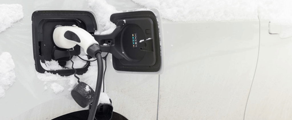 Pompe de chargement d'un véhicule électrique blanc en hiver avec de la neige 