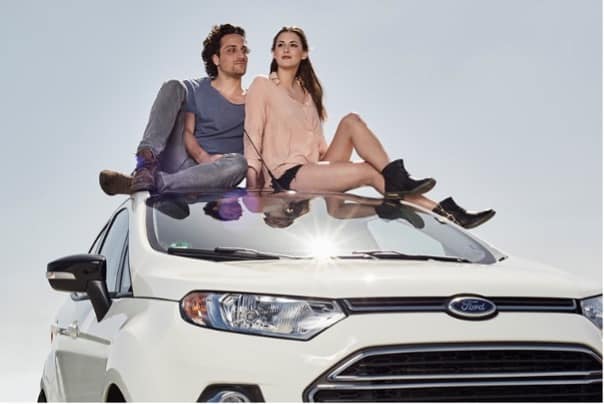 2 jeunes étudiant assis sur le toit d'une voiture blanche